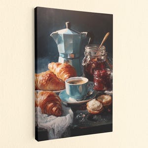 May include: A canvas print depicting a still life scene with a silver moka pot, a light blue coffee cup on a matching saucer, three golden-brown croissants on a white cloth, and two glass jars containing dark red jam with a wooden spoon.