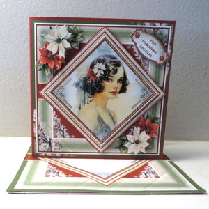 May include: A handmade Christmas card with a vintage design featuring a woman in a glamorous dress and a poinsettia flower. The card has a red, green, and white color scheme and includes the text "For Someone Special".