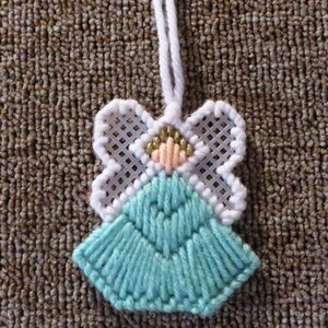 May include: A white and turquoise angel ornament with gold glitter accents. The angel is made of yarn and has a white loop for hanging.