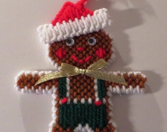 May include: A brown gingerbread man Christmas ornament with a white trim, red and white Santa hat, green pants, and a gold ribbon.