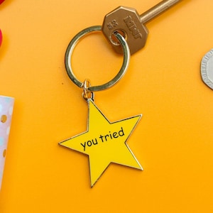 May include: A gold key chain with a yellow star charm that says "you tried".