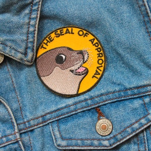 May include: A yellow and brown embroidered patch with a seal and the text "The Seal of Approval".