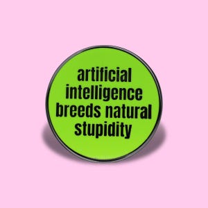 May include: A circular pin with a bright lime green background and a thin black border. The text "artificial intelligence breeds natural stupidity" is printed in bold, black, sans-serif capital letters across the center of the circular surface.
