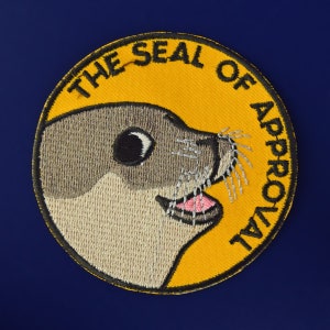 May include: A yellow embroidered patch with a cartoon seal and the text "The Seal of Approval".