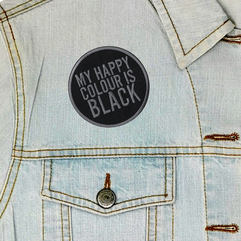 May include: A black and grey embroidered patch with the text "My Happy Colour Is Black" on a light blue denim jacket.