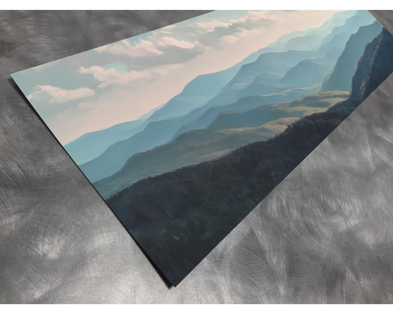 May include: A print of a mountain landscape in shades of blue and green, with a cloudy sky. The artwork depicts rolling hills and distant peaks, creating a sense of depth and tranquility. The print is displayed at an angle.