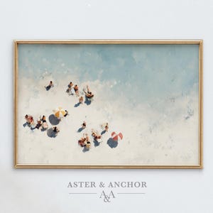 May include: A framed print of a beach scene, featuring people with umbrellas and beach chairs on a sandy shore. The artwork has a watercolor style with a gold frame and the text "ASTER & ANCHOR" at the bottom.