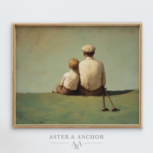 May include: A framed vintage-style print depicts two figures seated on a grassy hill, facing away from the viewer. The figures are dressed in light-colored shirts and pants. Golf clubs rest on the ground. The print is framed in a gold-colored frame.