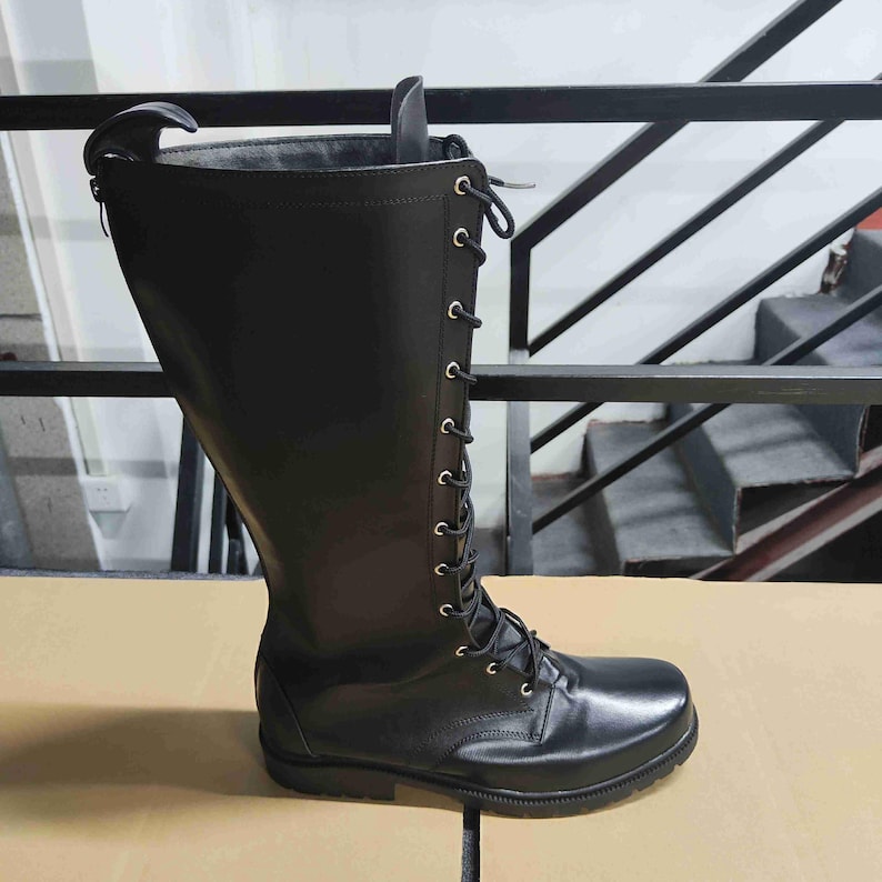 Puede incluir: Una bota alta de color negro con acabado liso, punta redondeada y cierre frontal de cordones con ojales met&aacute;licos plateados. La bota incluye una cremallera vertical a lo largo de la parte trasera de la ca&ntilde;a y una suela de goma negra resistente.