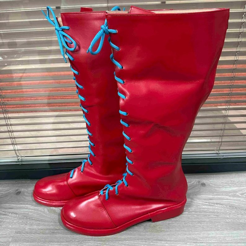 May include: A pair of tall, red boots with light blue laces. The boots are knee-high with a smooth, glossy finish. The laces are threaded through eyelets up the front of the boots.