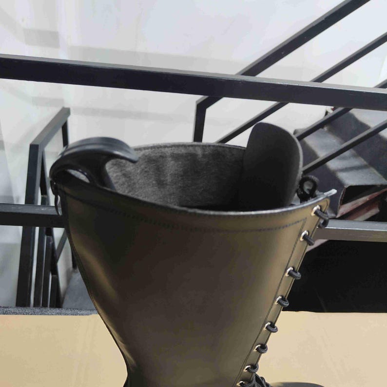 Puede incluir: Una bota alta de color negro con un acabado exterior liso, un forro interior gris oscuro y una fila vertical de ojales met&aacute;licos de color plateado en el lateral. Un calzador de pl&aacute;stico negro est&aacute; insertado en la abertura superior.