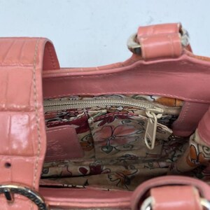 Peut inclure: Un sac &agrave; main corail avec un motif textur&eacute; imitation crocodile. L'int&eacute;rieur pr&eacute;sente une doublure &agrave; imprim&eacute; floral et une poche zipp&eacute;e. Le sac a une base tiss&eacute;e et une poign&eacute;e en cuir corail avec des &eacute;l&eacute;ments m&eacute;talliques.