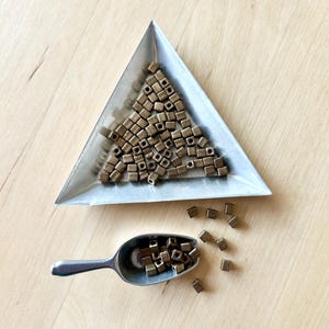 May include: A trio of ceramic mugs with a speckled, matte finish in cream, light grey, and dark grey. Each mug features a simple, minimalist design and a rounded handle.