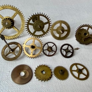 May include: A collection of various brass clock gears, showcasing different sizes and designs. The gears range in color from gold to bronze, with intricate teeth and central holes. Some gears have spokes, while others are solid.
