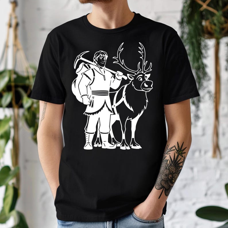 May include: Black t-shirt featuring a white graphic of a character with a pickaxe and a reindeer. The character is wearing a tunic and boots. The reindeer has large antlers and a harness. The design is a cartoon style.
