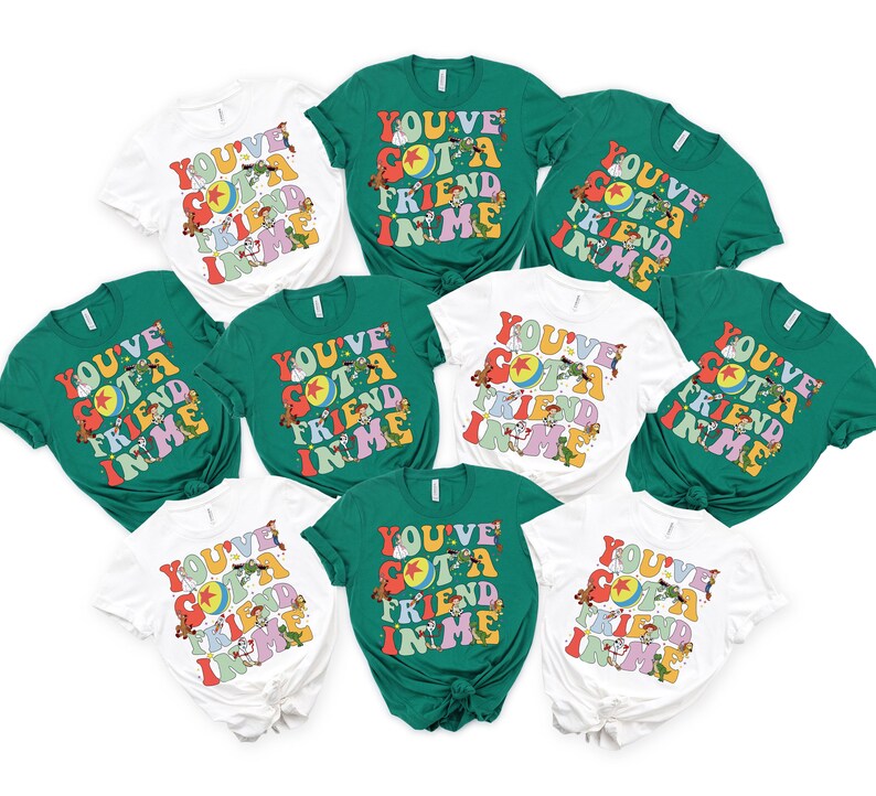 May include: A collection of white and green t-shirts with the text "YOU'VE GOT A FRIEND IN ME" in a retro font. The shirts feature cartoon characters and a colorful design, perfect for fans of the movie.