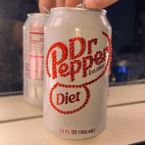 May include: A white Diet Dr. Pepper can with red rhinestone embellishments. The text "Dr Pepper Est. 1885" and "Diet" are visible. The can is 12 fl oz (355 mL).