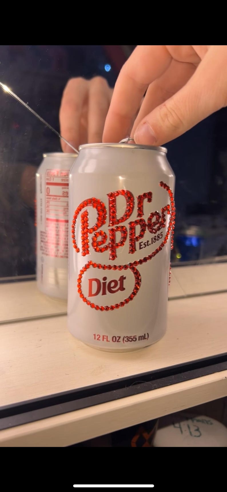 May include: A white Diet Dr. Pepper can with red rhinestone embellishments. The text "Dr Pepper Est. 1885" and "Diet" are visible. The can is 12 fl oz (355 mL).