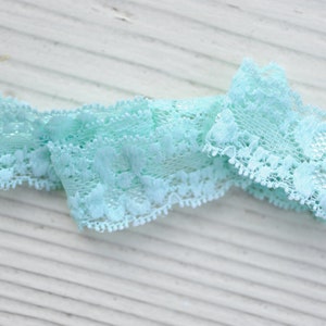 May include: A light blue lace trim with a delicate floral pattern. The trim is soft and flexible, making it ideal for adding a touch of elegance to any project.