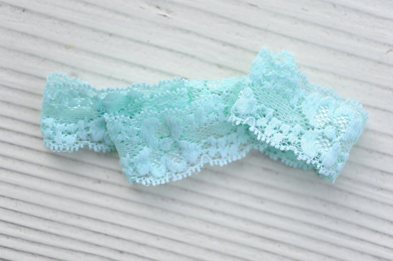 May include: A light blue lace trim with a delicate floral pattern. The trim is soft and flexible, making it ideal for adding a touch of elegance to any project.