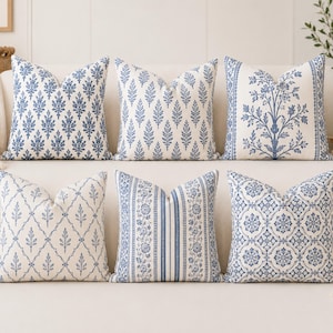 Puede incluir: Un conjunto de seis cojines cuadrados con varios patrones en azul y blanco. Los diseños incluyen motivos de hojas repetidos, un estampado botánico central con bordes laterales, un patrón de celosía de diamantes, rayas florales y azulejos geométricos.