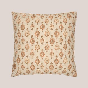 May include: A square throw pillow featuring a cream-colored fabric base with a repeating pattern of small, symmetrical floral motifs in shades of burnt orange and muted brown, arranged in vertical columns across the entire surface of the cushion.