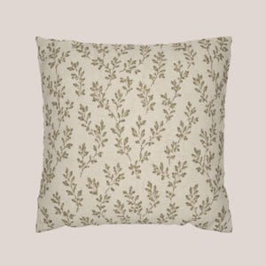 May include: A square throw pillow featuring an off-white or cream-colored fabric base. The surface is decorated with a repeating pattern of small, delicate olive-green leafy vine sprigs arranged in a vertical, branching orientation across the cover.