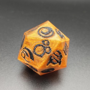 May include: An orange, multi-sided die with black symbols etched on each face. The die is a polyhedron, likely used for tabletop gaming. The symbols are stylized and intricate, adding a decorative element to the functional object.