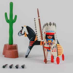 Peut inclure: Un ensemble de jouets comprenant un personnage amérindien avec une coiffe en plumes, une lance et un bouclier, monté sur un cheval noir avec des marques rouges. Un cactus vert et de petits accessoires noirs sont également inclus.