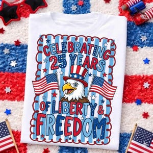 May include: White t-shirt with a patriotic design. The graphic features an eagle wearing a Uncle Sam hat, American flags, and the text "Celebrating 25 Years of Liberty & Freedom" in red and blue.
