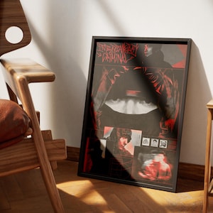 May include: A black framed poster with a red and black graphic design. The artwork features a central image of a person's face and the text "INTERPRETARY CRIMINAL". The poster is leaning against a wall next to a wooden chair.