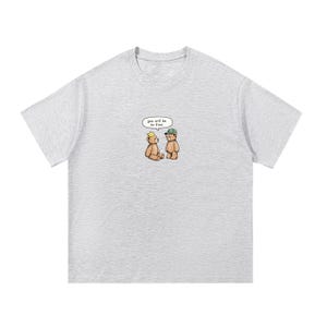 May include: Light gray t-shirt featuring a cartoon illustration of two teddy bears. One bear wears a crown, the other a cap. A speech bubble above them reads "you will be so fine."