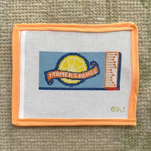 May include: Needlepoint canvas with a blue background and a yellow lemon design. The lemon is centered with a banner that reads "Summer Cruise". The canvas is framed with an orange border.