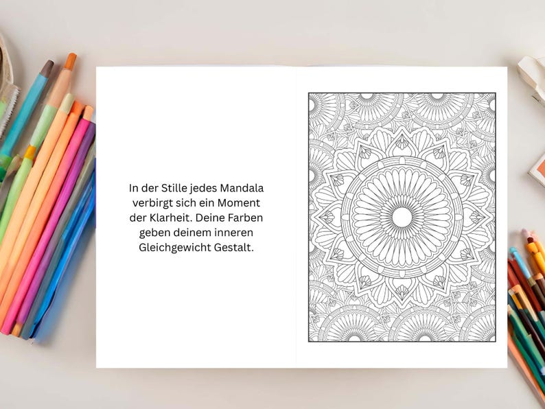 May include: Open book with a black and white mandala design on the right page. The left page has German text. Colored pencils are visible on the top and bottom of the image.