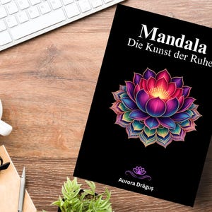 May include: A book titled "Mandala Die Kunst der Ruhe" with a vibrant lotus flower illustration on the cover. The cover is black with white text and a colorful floral design. The book is on a wooden surface.
