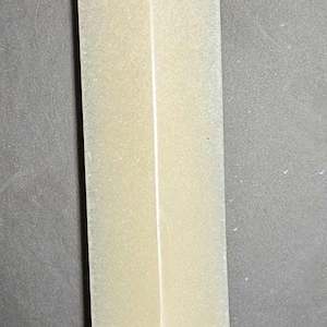 May include: A long, rectangular letter opener with a pale yellow handle and a silver-colored decorative end. The end features a detailed design of grapes and leaves.