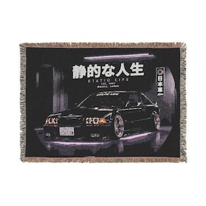 Könnte beinhalten: Schwarze Decke mit einem Autodesign, japanischem Text und den Worten "STATIC LIFE" und "OSAKA, JAPAN". Die Decke hat einen Fransenrand und ein dunkles, stimmungsvolles Design.