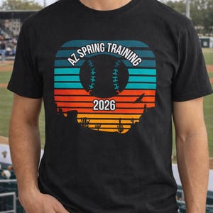 May include: Black t-shirt with a baseball-themed graphic. The design features the text "AZ SPRING TRAINING 2026" in a retro style, with a baseball silhouette and desert landscape.