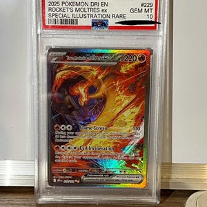 Może przedstawiać: Karta Pokémon z oceną z Rocket's Moltres ex, rzadką ilustracją specjalną. Karta jest zamknięta w ochronnym etui z tekstem "2025 POKEMON DRI EN" i "GEM MT 10". Grafika karty przedstawia płomiennego Moltresa.