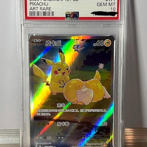 Può includere: Una carta Pokémon valutata con Pikachu, etichettata come "2025 Pokemon 151 CS Pikachu Art Rare #171 GEM MT 10". La carta presenta un design olografico con Pikachu e altri personaggi. La carta è racchiusa in un supporto protettivo di plastica.