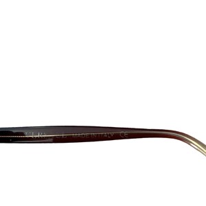 Pu&ograve; includere: Primo piano di una montatura di occhiali nera con un'asta color oro. Il testo "MADE IN ITALY" &egrave; visibile sulla montatura. Gli occhiali hanno un design elegante e moderno.