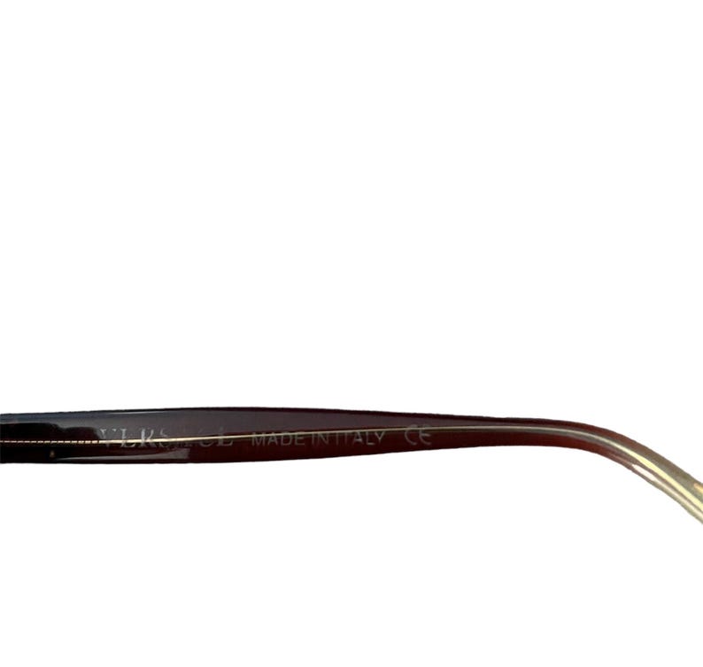 Pu&ograve; includere: Primo piano di una montatura di occhiali nera con un'asta color oro. Il testo "MADE IN ITALY" &egrave; visibile sulla montatura. Gli occhiali hanno un design elegante e moderno.