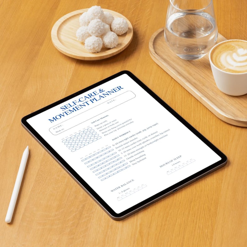 May include: A digital tablet displaying a "SELF-CARE & MOVEMENT PLANNER" with a white stylus on a wooden surface. The planner includes sections for daily workouts, water balance, and sleep tracking. A small wooden tray holds a glass of water and a cup of coffee.