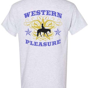 May include: Light gray t-shirt with a Western theme. The back of the shirt features the words "WESTERN PLEASURE" in blue, with a gold star and a silhouette of a person riding a horse. Two blue stars flank the central design.