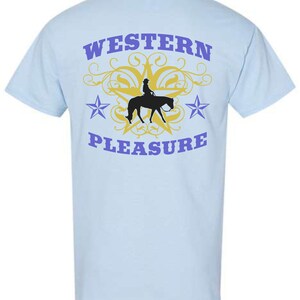 May include: Light blue t-shirt with a graphic design featuring a silhouette of a rider on a horse, a yellow star, and the words "WESTERN PLEASURE" in purple. The design includes two purple stars and decorative swirls.