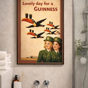 May include: Framed vintage-style Guinness advertisement. The artwork features toucans carrying pints of Guinness, with the text "Lovely day for a Guinness." Two women in green uniforms are also depicted.