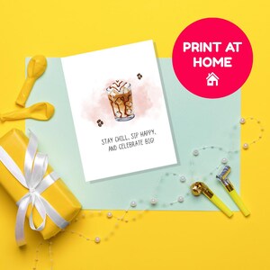 May include: A greeting card with an illustration of an iced coffee drink with the text "Stay Chill, Sip Happy, and Celebrate Big!". The card is on a light blue surface, with a yellow gift box, balloons, and party favors. A red circle with "Print at Home" is in the background.