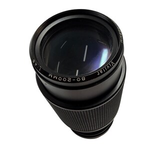 May include: A black Vivitar 80-200mm 1:4.5 camera zoom lens with a 55mm filter thread size. The lens features a textured rubber grip ring around the barrel and white printed text detailing the focal length, aperture, and brand name on the front.