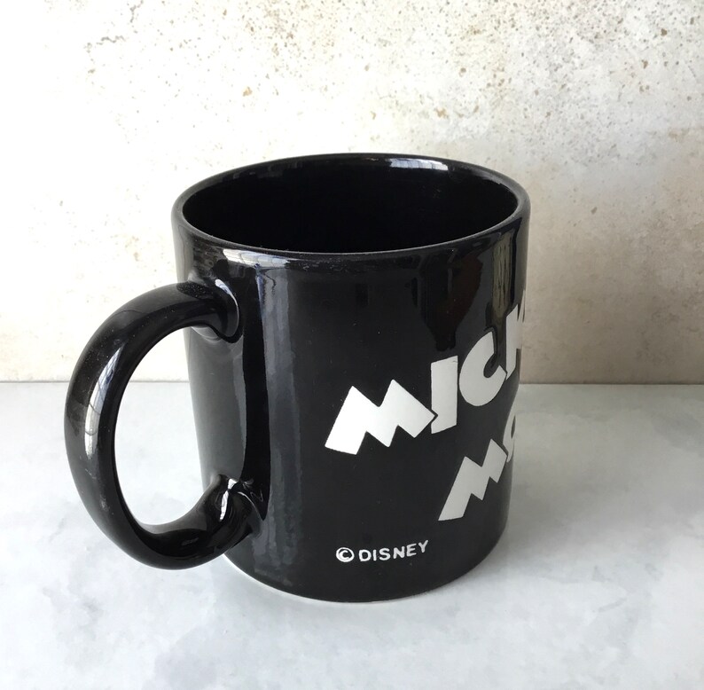 May include: Black ceramic mug with a white Mickey Mouse design and the word "DISNEY" printed on the bottom.