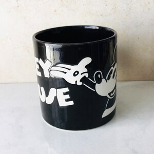 May include: Black ceramic mug with a white image of Mickey Mouse and the text "Disney Mouse" on the side.